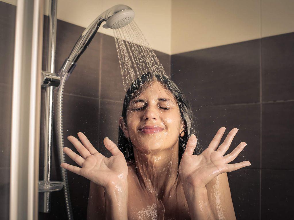 Junges Mädchen das gut gelaunt unter der Dusche steht